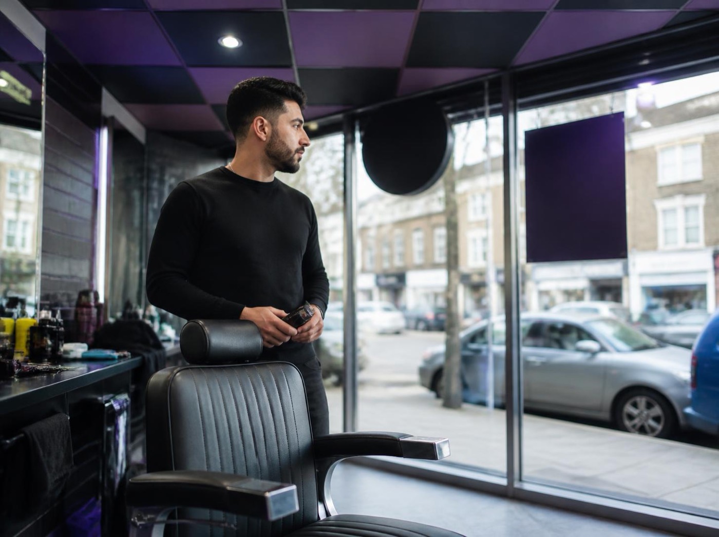 A barber beside an empty chair, looking out of the shop window