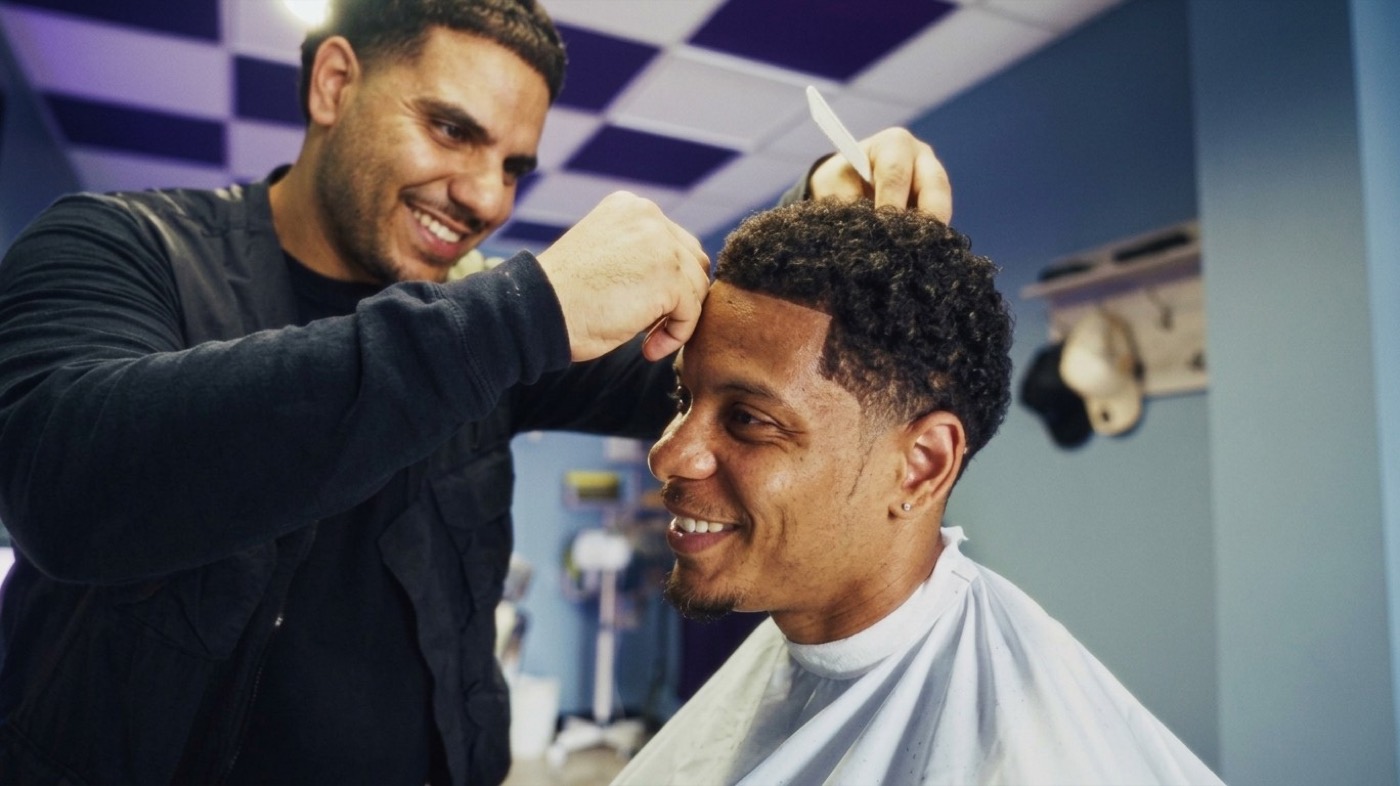 A barber combing a smiling client's curly hair