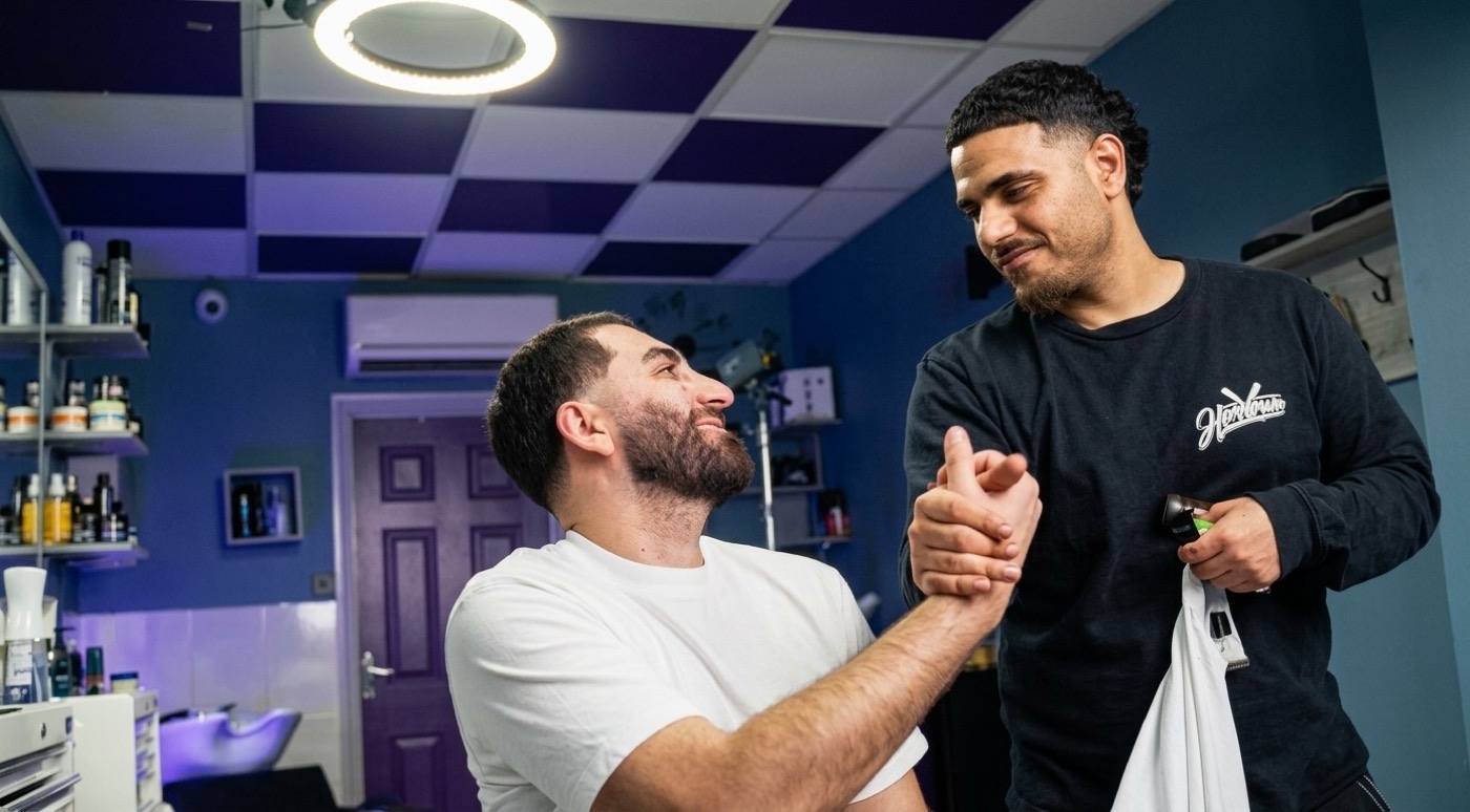 A barber shaking hands with a client in his shop